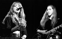 black and white photo of two women singing and playing guitars