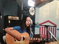 a girl playing an acoustic guitar in front of a microphone
