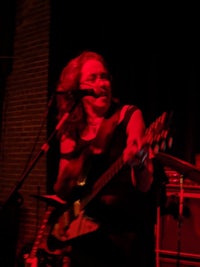 a woman playing a guitar in front of a red light