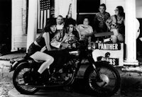 a group of people sitting on a motorcycle in front of a house